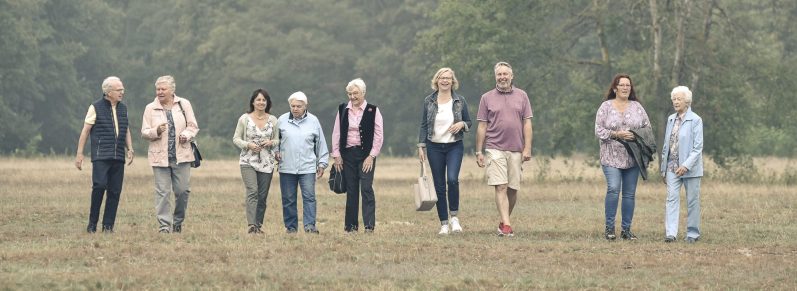 Die 10 Personen des Entwicklerteams des Schatzkästchens Das Entwicklerteam des Schatzkästchens - Erinnerungsbuch für Erwachsene ab 50 - ist unterwegs auf einer Wiese.