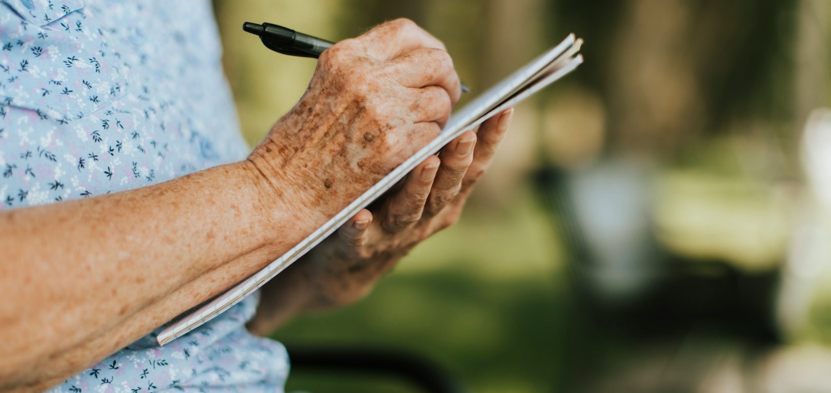 Aufschreiben Ältere Person hält einen Stift und schreibt etwas auf